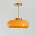 Luna Amber Glass Pendant Light with brushed brass finish on a light gray background.